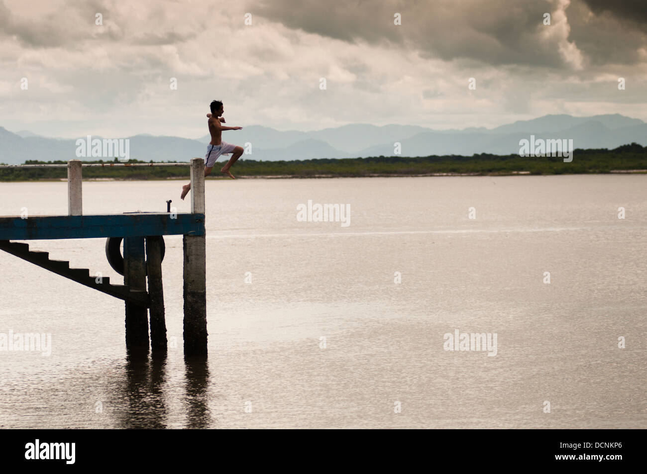 Kid sautant d'embarcadère pour l'amusement à Ilha das Peças (PECA), l'île de la baie de Paranaguá, l'Etat du Parana, Brésil. Banque D'Images