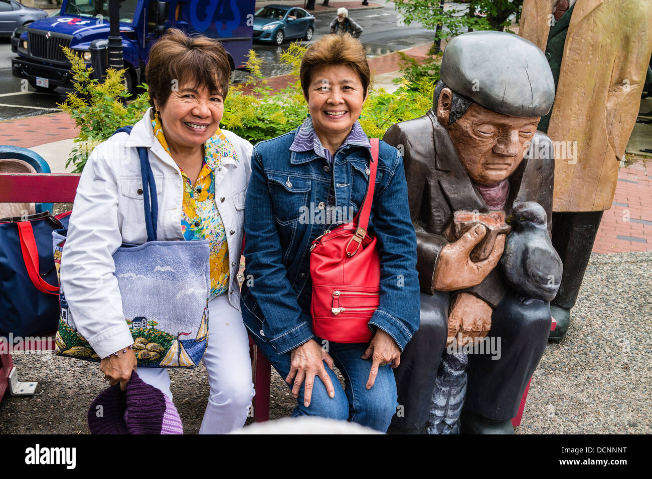 Les touristes asiatiques posant avec un immense, plus grand que nature, groupe de sculptures en bois à St John, Nova Scotia, Canada. Banque D'Images