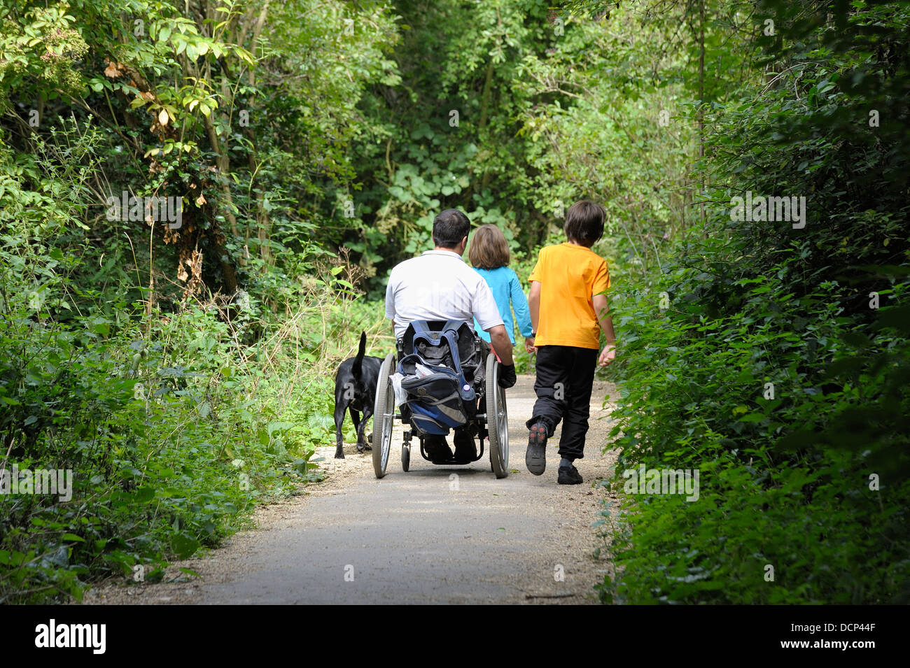 Un homme handicapé dans un fauteuil roulant avec ses enfants sur un sentier public England uk Banque D'Images