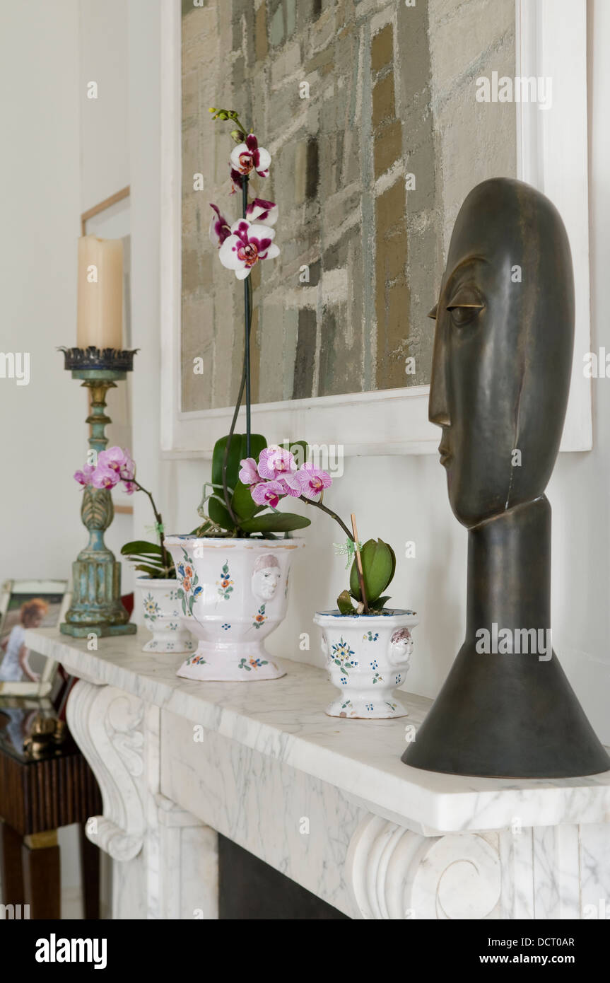 Buste sculptural et d'orchidées sur la cheminée en marbre Banque D'Images