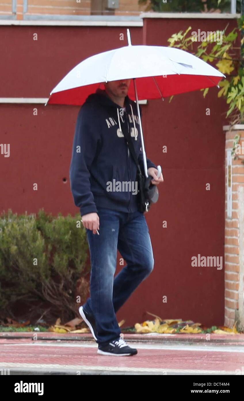 Le Real Madrid et l'Espagne gardien Iker Casillas prend son chien pour une  promenade, tenant un parapluie sous la pluie. Le capitaine gagnant de la  Coupe du monde s'est arrêté pour signer