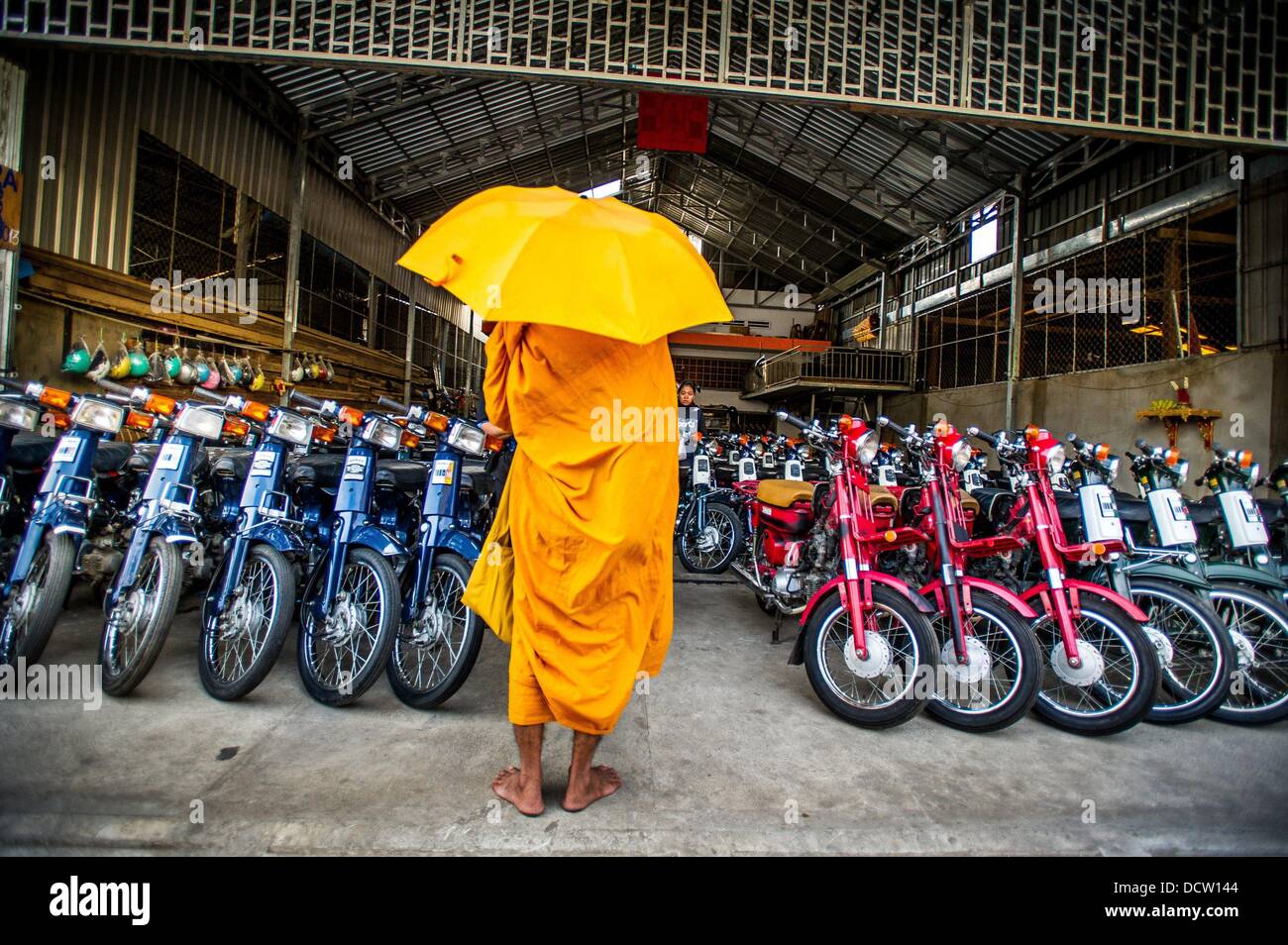 Le 4 janvier 2013 - Phnom Penh, Cambodge - Jan 4, 2013 - un moine bouddhiste est en attente de la nourriture à un shop de nouveaux cyclomoteurs dans la capitale cambodgienne de Phnom Penh ville...Histoire Résumé : Au milieu du rythme effréné de Phnom PenhÌ severnãƒ les rues de la ville, une véritable bête de transport pour les personnes et les marchandises qui émerge, vélos, motos, scooters, mobylettes, et motodups Tuk Tuks errent à la place des voitures et des camions. Près de 90  % des véhicules sur la capitale cambodgienne de près de 2,3 millions de personnes choisissent ces pour se déplacer. La congestion et l'environnement à la fois profiter de la petite taille et de petits moteurs. Busines Banque D'Images