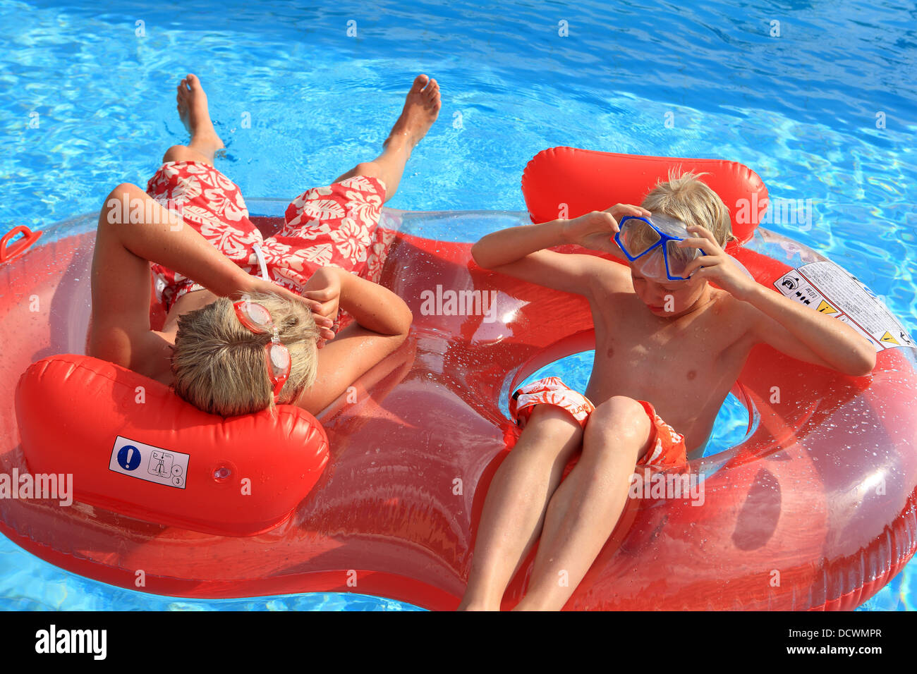 Les jeunes garçons se détendre et bavarder sur un lit gonflable annelé dans la piscine Banque D'Images