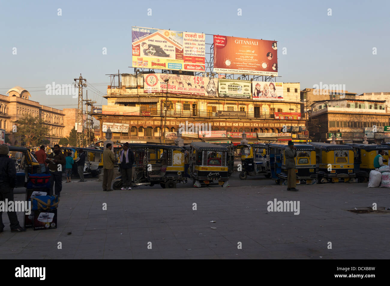 Un certain nombre de personnes, les rickshaws auto parqué et boutiques à l'extérieur de la gare de Jodhpur tôt le matin avec la lumière du soleil vers le haut Banque D'Images