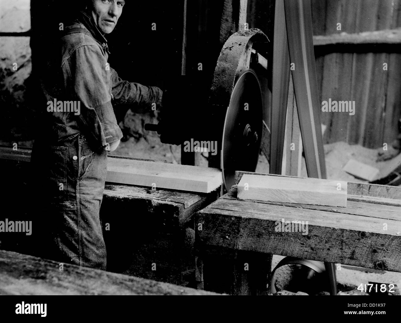 Une planche est coupée dans une usine, ce qui fait partie du processus de production de matériaux en bois. Des moulins comme celui-ci étaient cruciaux pour les industries du bois d'œuvre et de la construction à l'ère industrielle. Banque D'Images