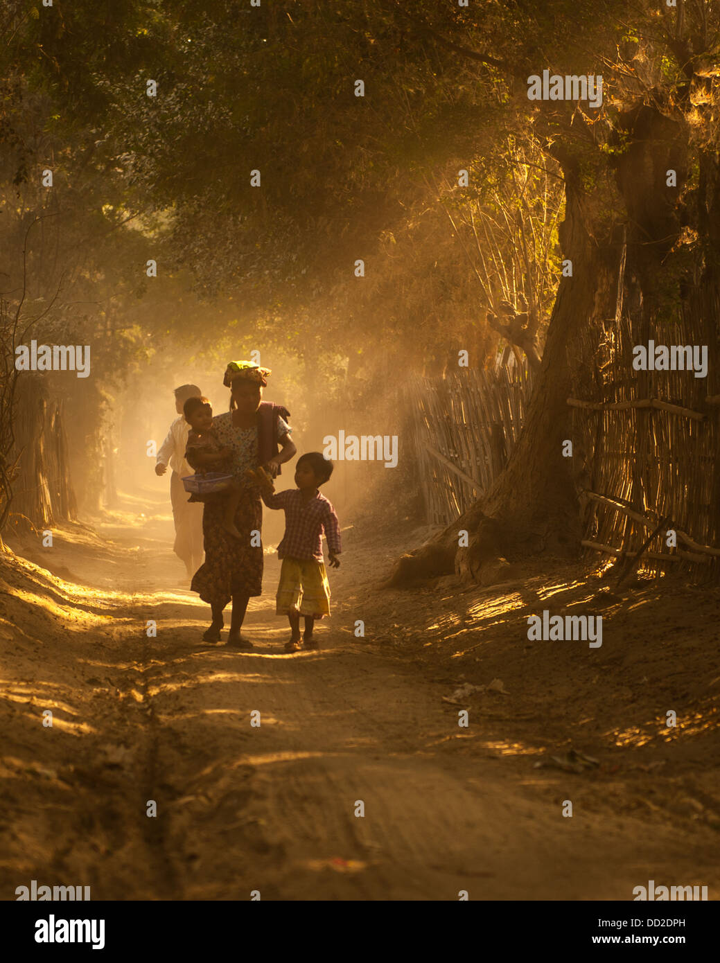 Mère et enfants marchant sur route poussiéreuse Birmanie Myanmar Banque D'Images