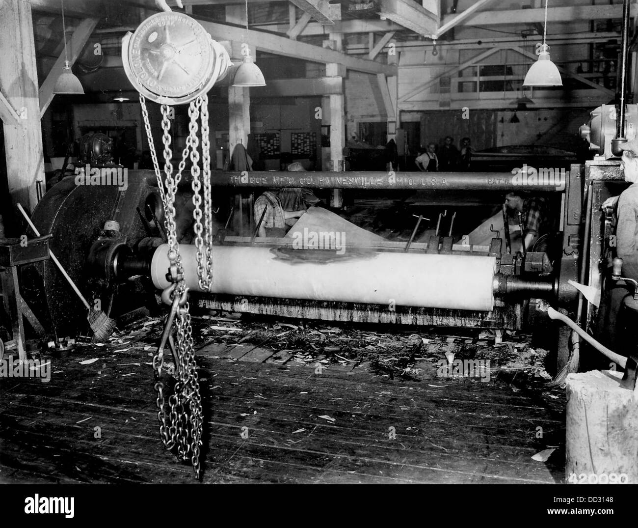 Cette image montre le processus de découpe du placage, une fine couche de bois, probablement pour les meubles ou les matériaux de construction. La photographie capture le savoir-faire artisanal impliqué dans l'industrie du travail du bois, soulignant la précision et l'habileté requises pour couper le placage. Banque D'Images