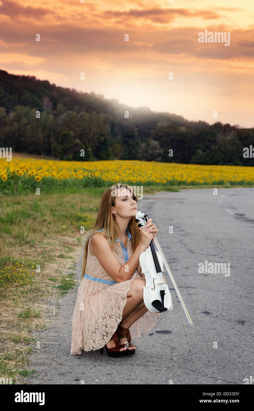 Jeune femme seule avec siège de violon par country road Banque D'Images