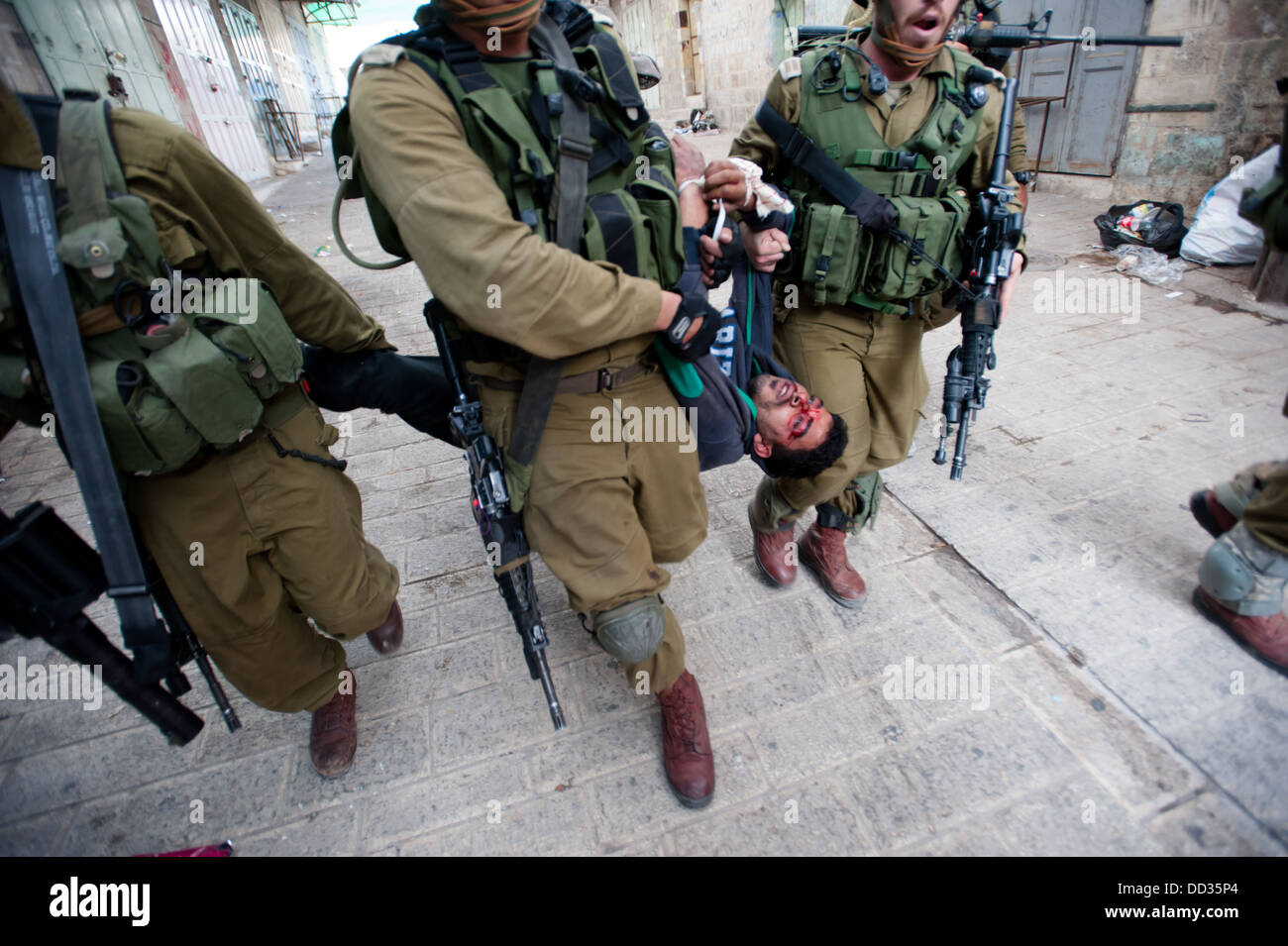 Des soldats israéliens ont arrêté un jeune Palestinien, qui montre des signes d'être battu, suite à une manifestation à Hébron, en Cisjordanie. Banque D'Images