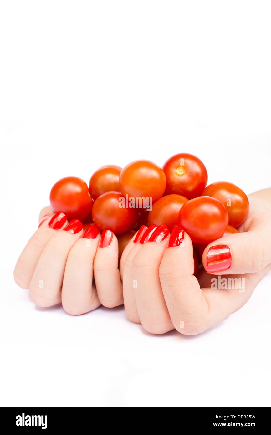 Deux mains avec orange ongles tenant tomates cerise Banque D'Images