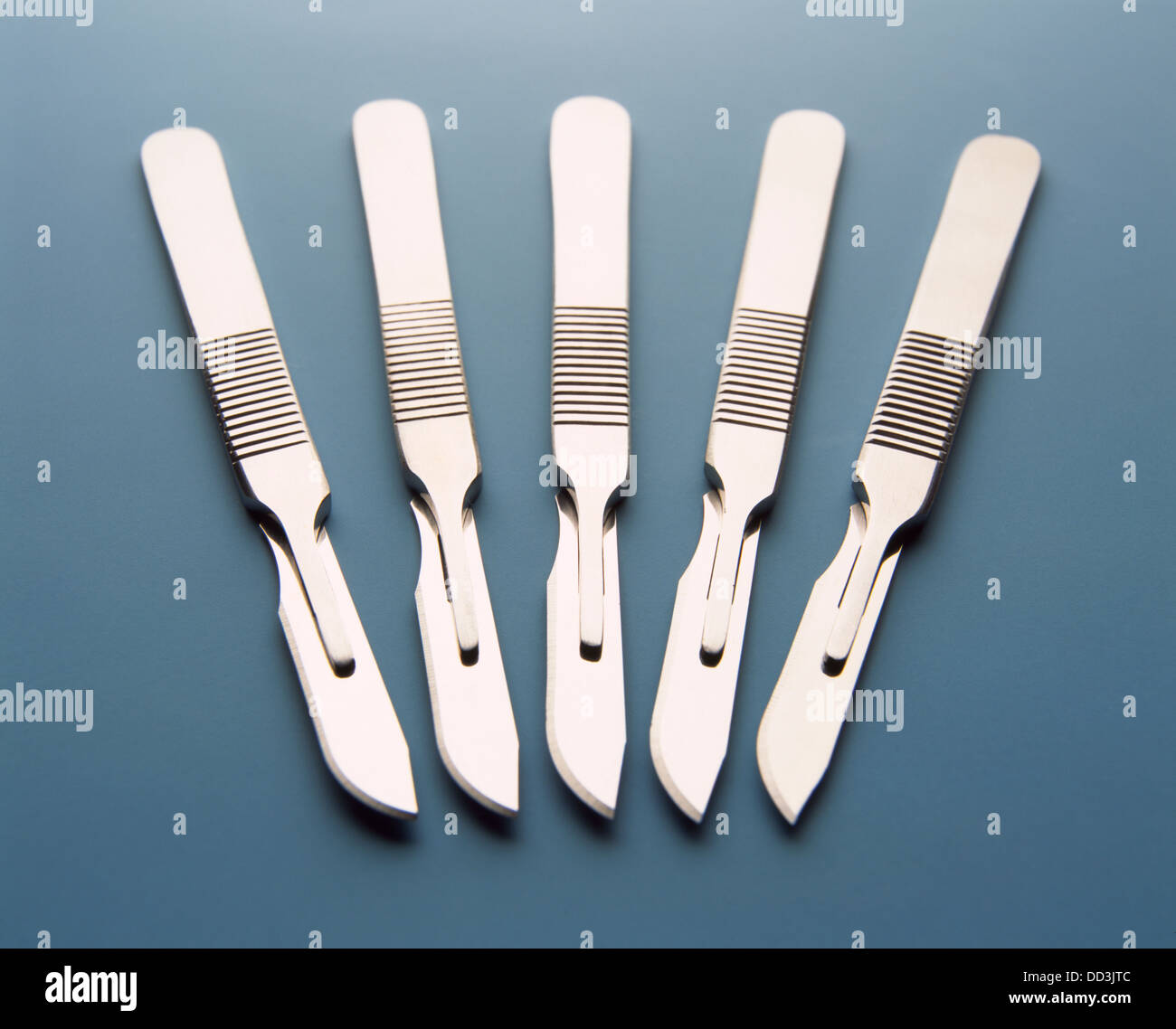 Cinq couteaux scalpel métal sur fond bleu Banque D'Images