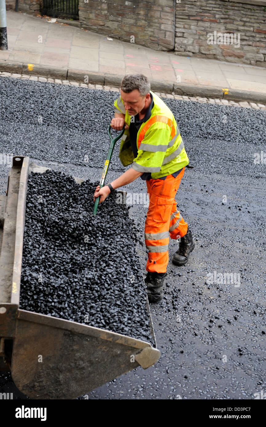 La collecte d'asphalte Workman godet de chargeuse avant de diffuser au cours de la réparation et de resurfaçage des routes Banque D'Images