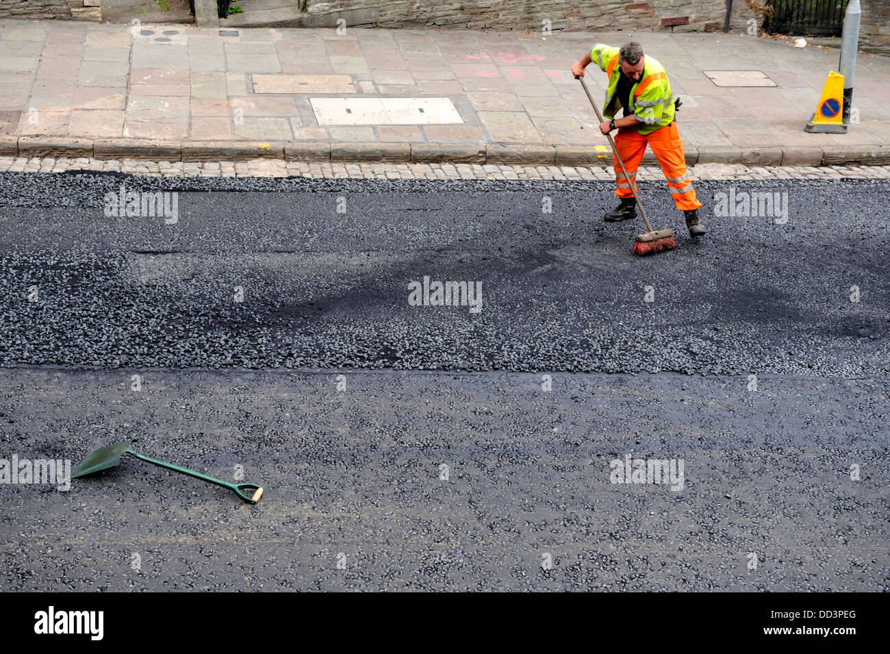 À l'aide d'asphalte Workman balai se propager au cours de réasphaltage Banque D'Images