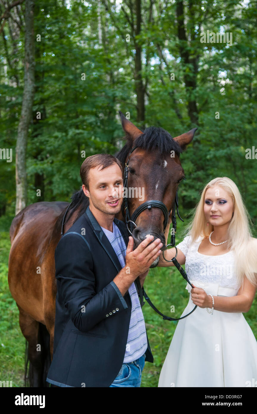 Belle mariée et le marié avec un cheval dans la forêt. Se concentrer sur un groom et un cheval. Banque D'Images