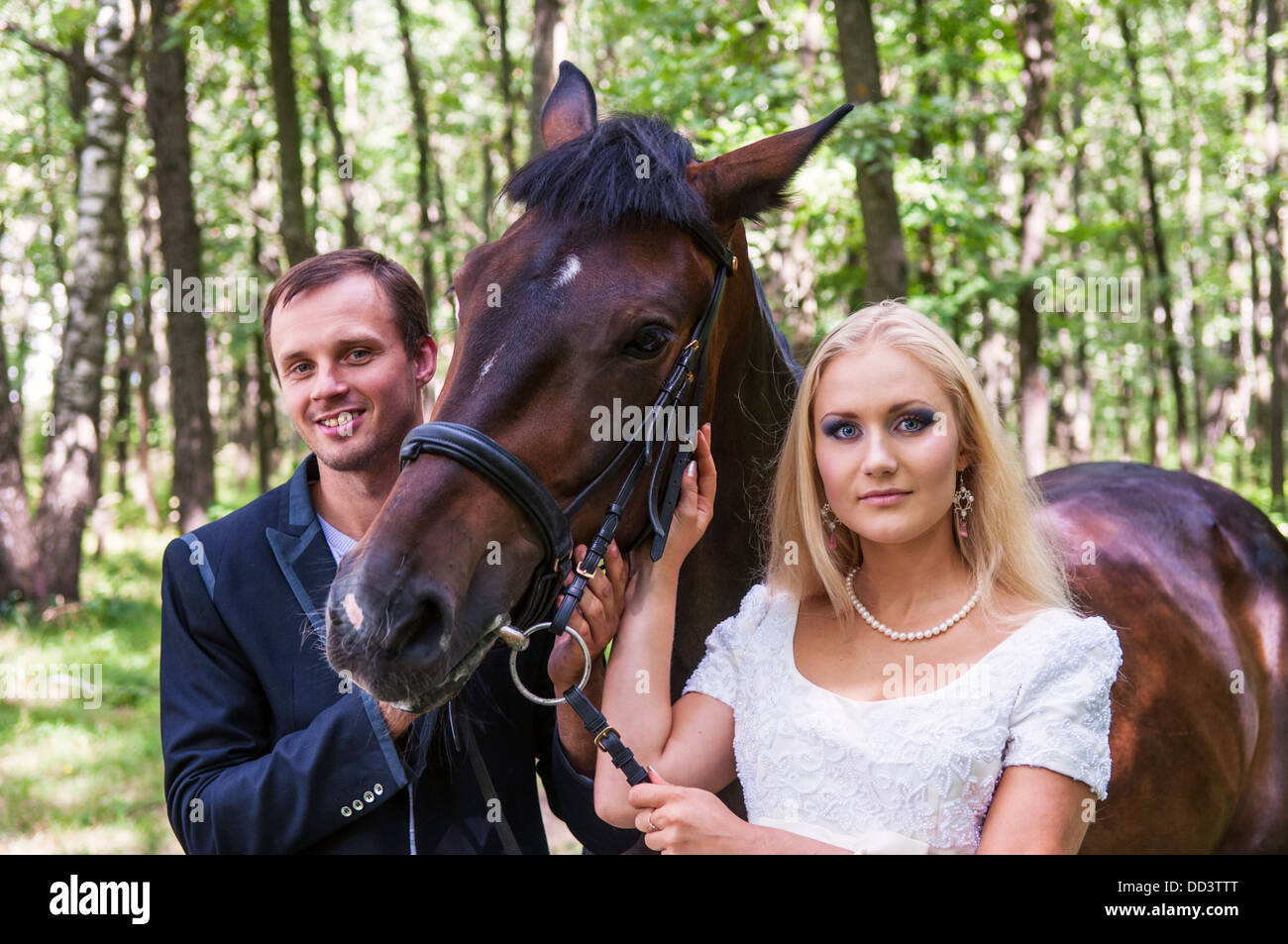 Belle mariée et le marié avec un cheval dans la forêt Banque D'Images