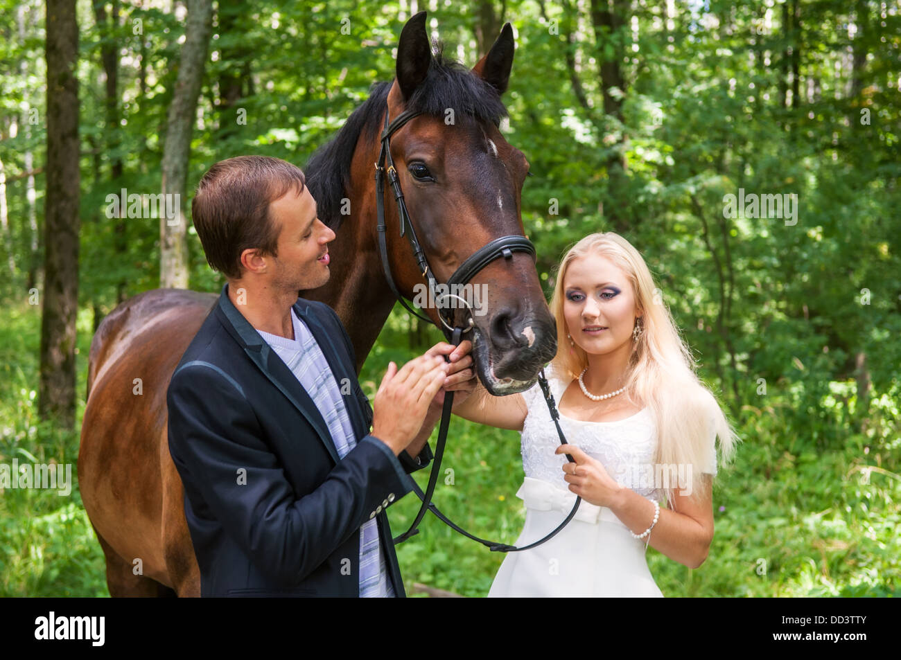 Belle mariée et le marié avec un cheval dans la forêt Banque D'Images