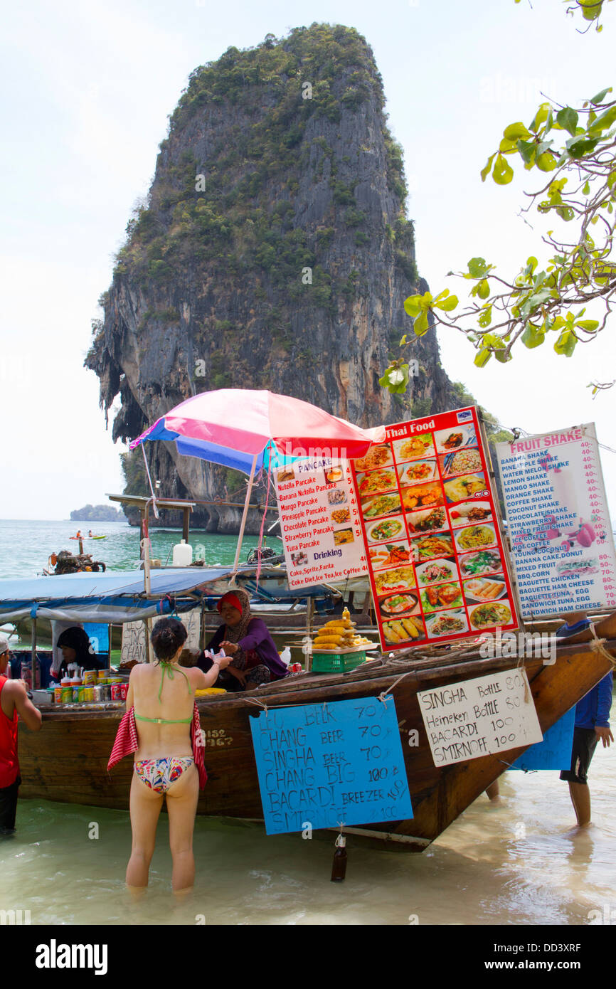 Une femme achète la nourriture dans un restaurant bateau ancré sur la plage de Hat Phra Nang Railay dans. Banque D'Images