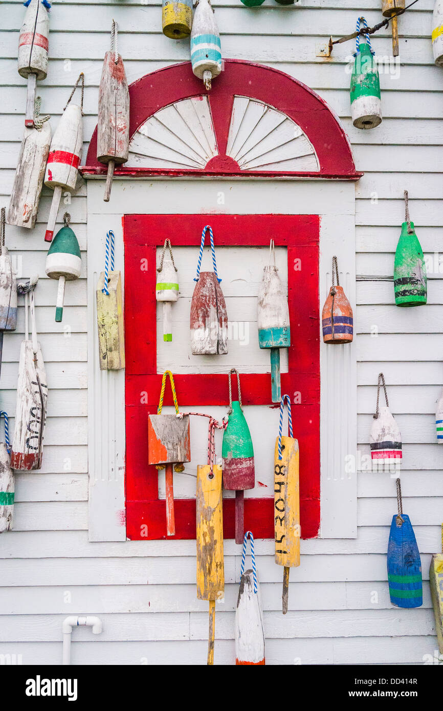 Des bouées de couleurs utilisées dans la pêche du homard et du crabe accroché au côté d'un bâtiment dans le Maine. Banque D'Images