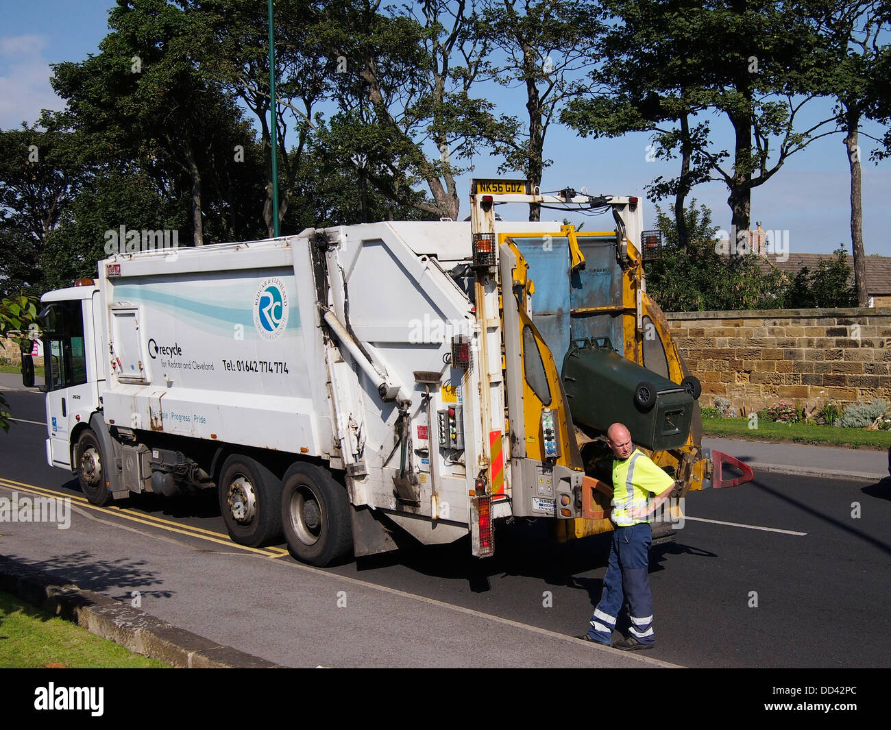 L'homme travaillant à l'arrière d'un véhicule d'élimination des déchets vidange d'un wheelie bin pour le recyclage des déchets de jardin Banque D'Images