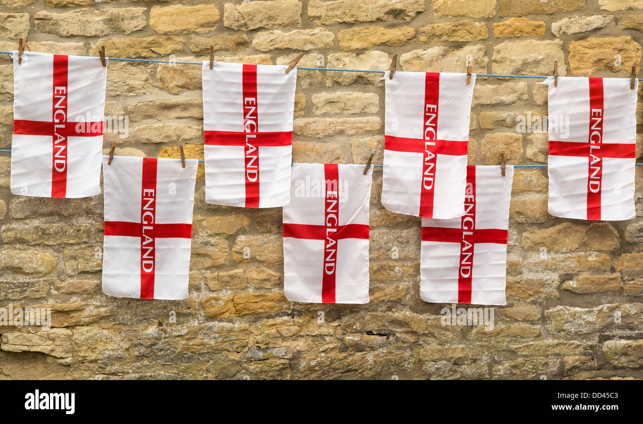 Drapeaux de l'Angleterre sur les lignes d'ancrage contre un mur en pierre de Cotswold. Cotswolds, Royaume-Uni Banque D'Images