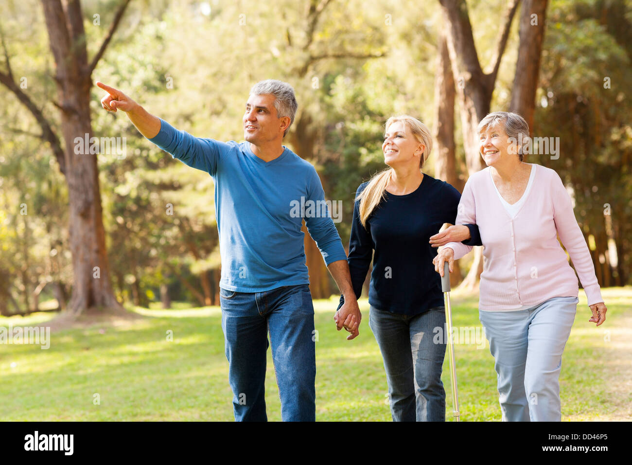 Cheerful couple d'âge moyen en tenant sa mère âgée pour une promenade en forêt Banque D'Images
