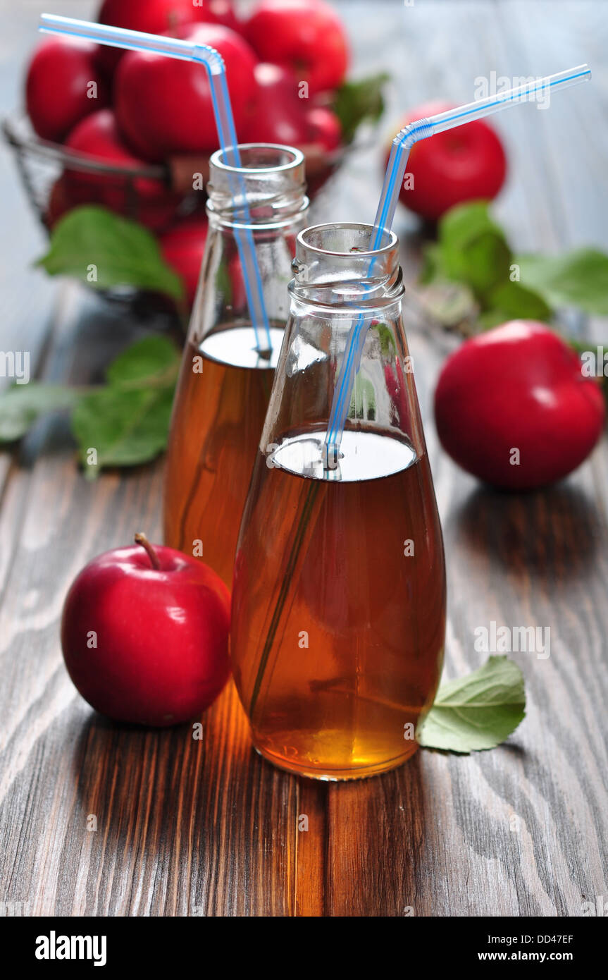 Le cidre en bouteille en verre et panier avec des pommes fraîches Banque D'Images