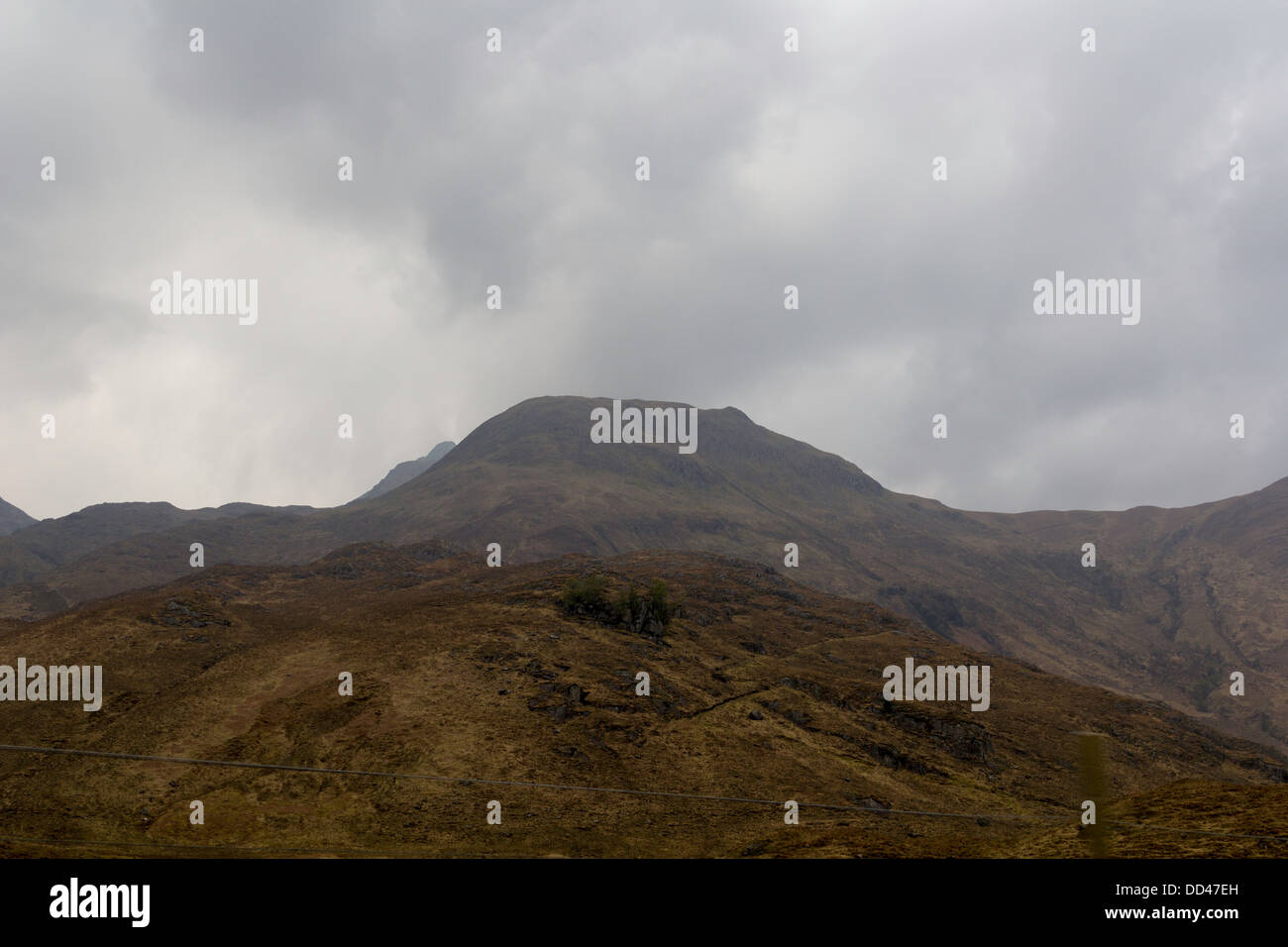 La pente douce d'une colline dans les Highlands écossais sur la rive d'un lac, à frotter partout et un ciel nuageux Banque D'Images
