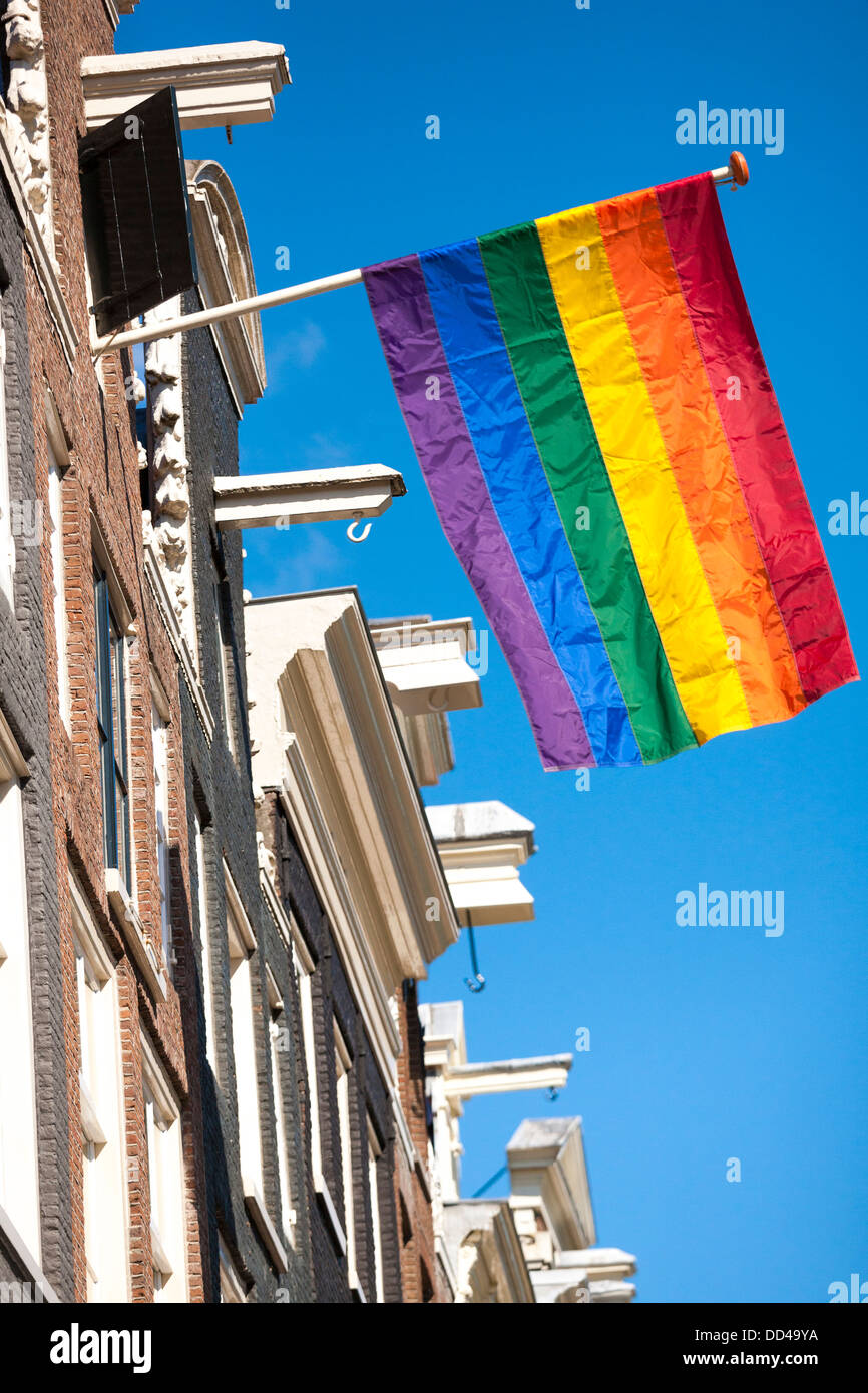De couleur arc-en-ciel drapeau flotte à partir d'une rangée de maisons typiques du canal à Amsterdam pendant l'émancipation LGBT Gay Pride, manifestation. Banque D'Images