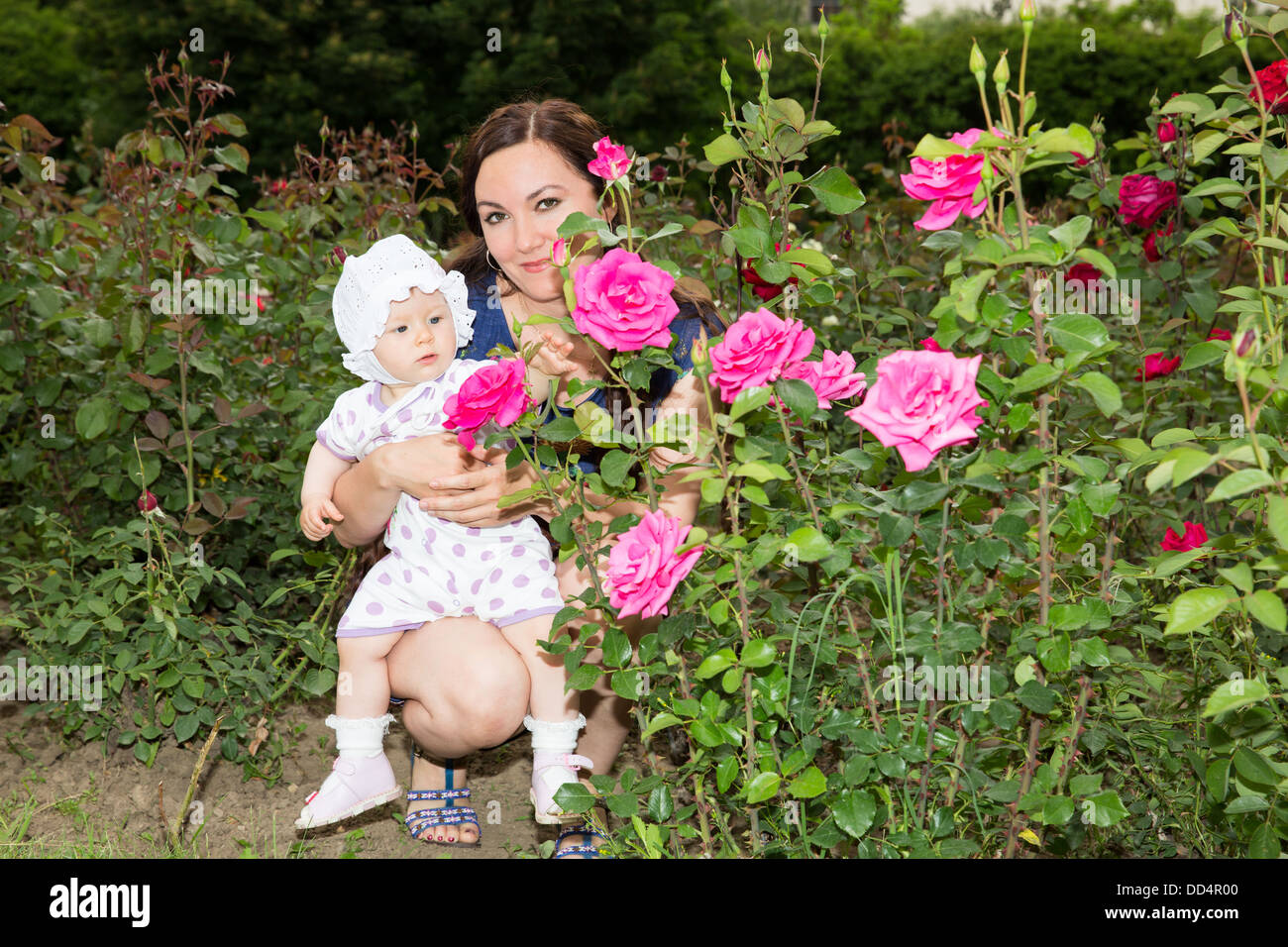 Heureux maman et enfant girl hugging en fleurs. La notion d'enfance et de la famille. Belle Mère et son bébé à l'extérieur Banque D'Images