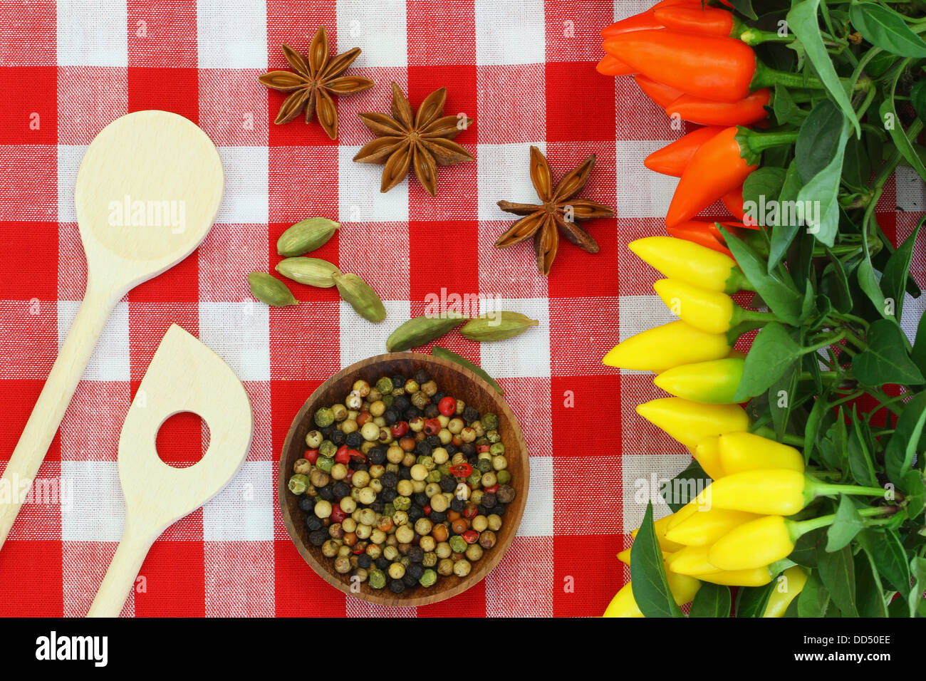 Épices, piments et de cuillères en bois sur nappe à carreaux Banque D'Images