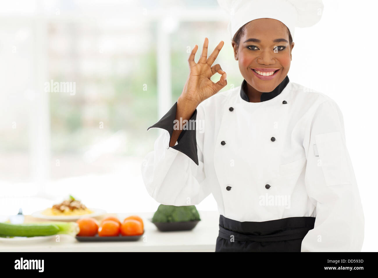 Belle jeune chef africain en cuisine de l'hôtel donnant ok sign Banque D'Images