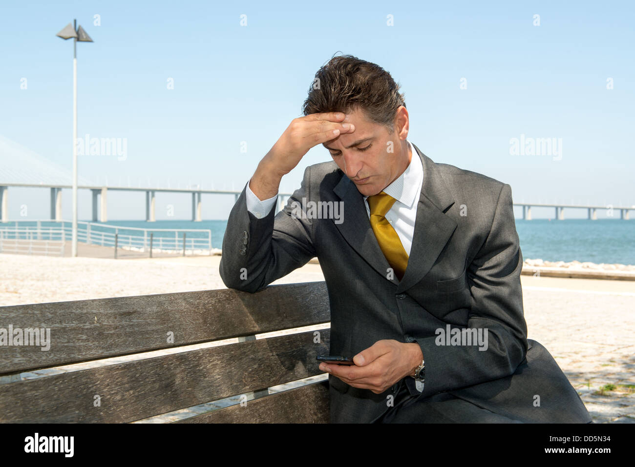 Inquiets businessman in a park bench with cellphone Banque D'Images