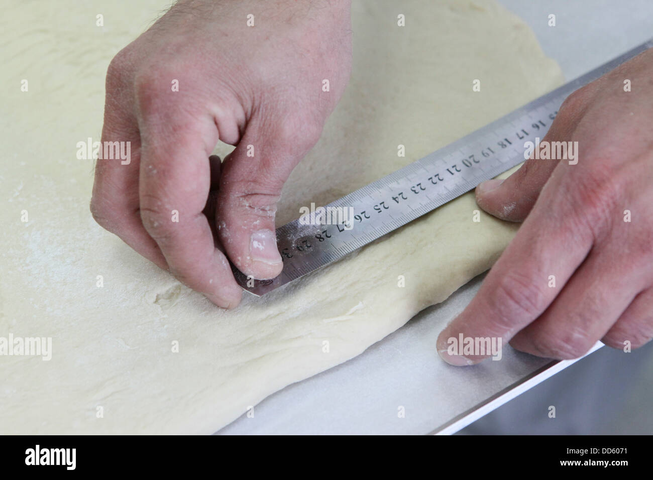Faire de la pâte feuilletée dans une boulangerie. Mesures Baker la pâte Banque D'Images