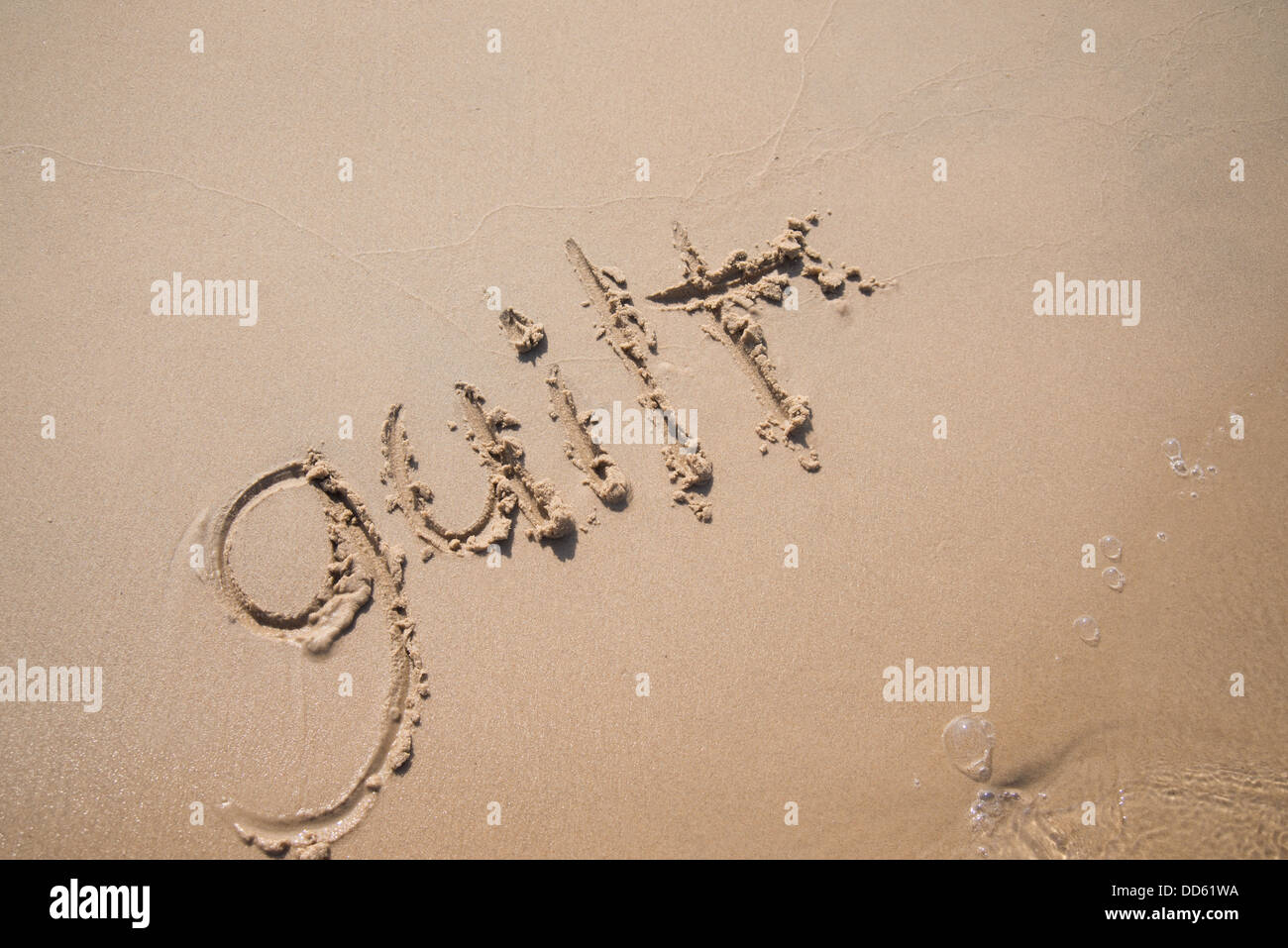 Le mot "culpabilité" écrit dans le sable, être emportée par une vague. Banque D'Images