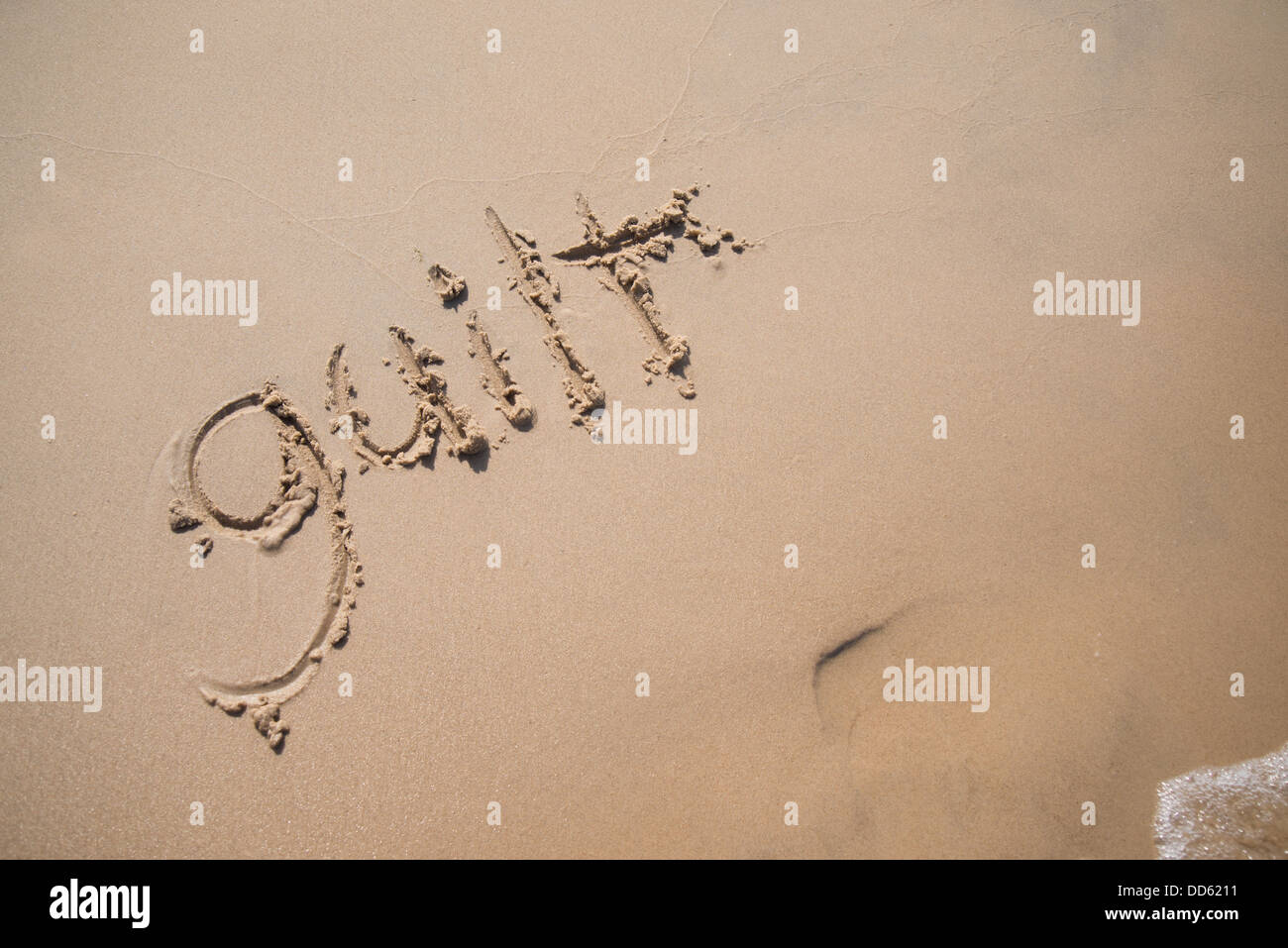 Le mot "culpabilité" écrit dans le sable, être emportée par une vague. Banque D'Images