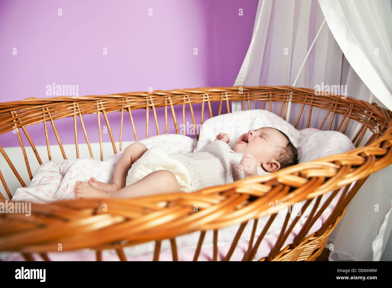 Baby Girl crying et couché dans berceau d'osier Photo Stock - Alamy