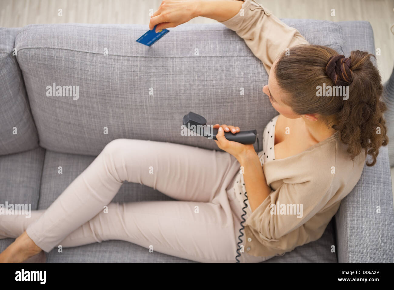Young woman sitting on couch avec carte de crédit et téléphone Banque D'Images