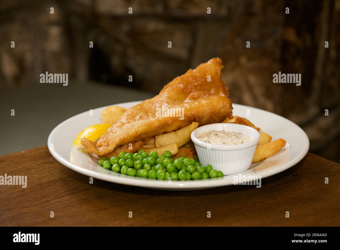 Fish, chips, petits pois et sauce tartare sur une assiette blanche dans un pub Banque D'Images