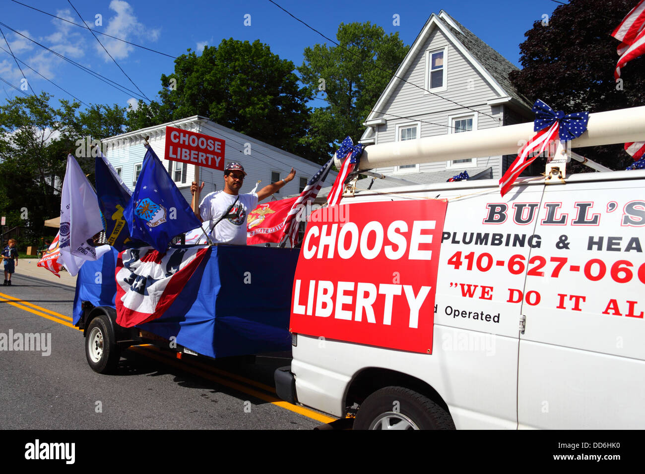 Man Holding Choose Liberty Sign in Trailer derrière le minibus d'affaires local pendant le 4th juillet Parades Independence Day, Catonsville, Maryland, États-Unis Banque D'Images