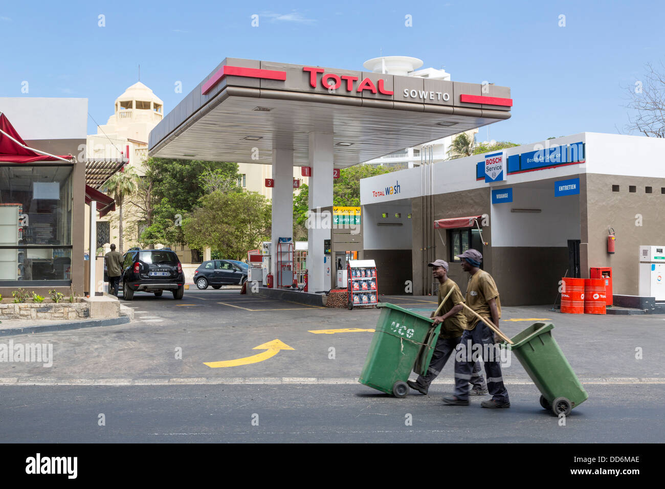 Dakar, Sénégal. Station d'essence moderne, deux nettoyeurs de rue en marche. Banque D'Images