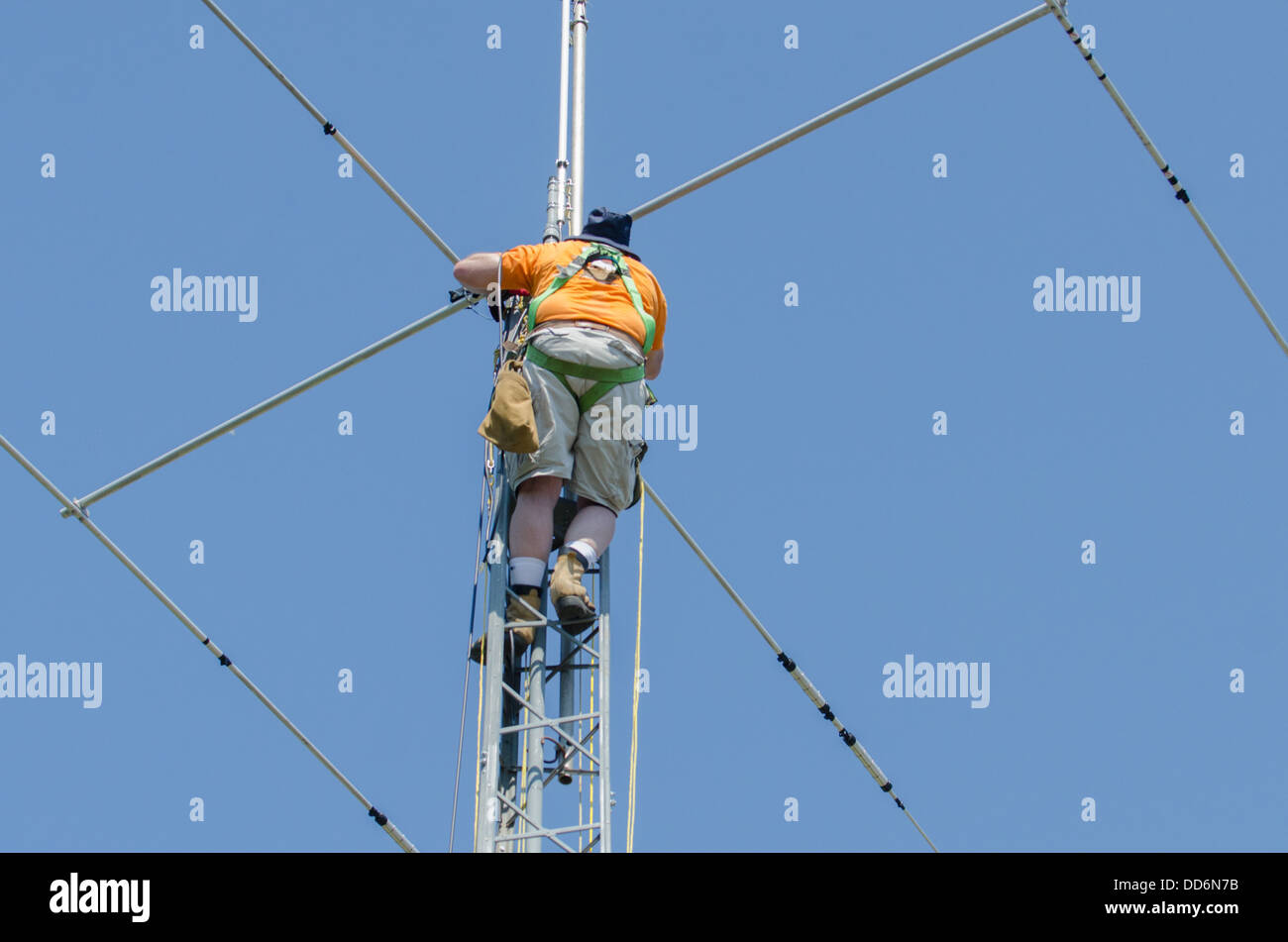 L'homme dans le harnais de sécurité de l'installation d'une tour de radio amateur et de l'antenne. Banque D'Images