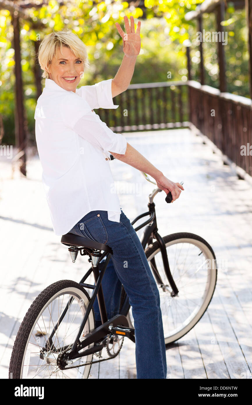 Cheerful femme d'âge moyen dans un vélo waving goodbye Banque D'Images