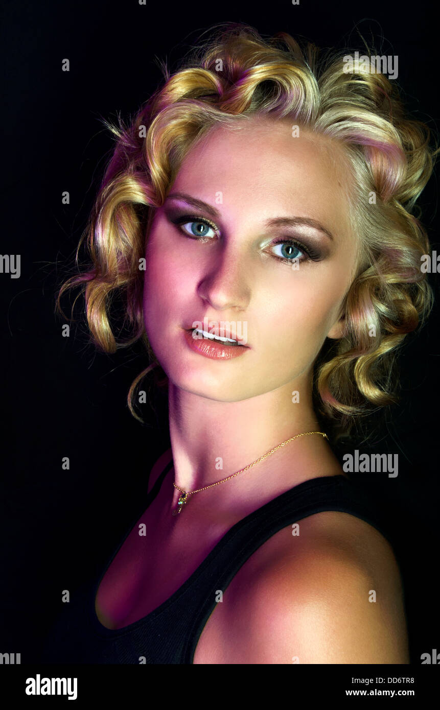 Un modèle de beauté pose farouchement en studio, l'éclairage dramatique avec cheveux inspiré de Marilyn Monroe Banque D'Images