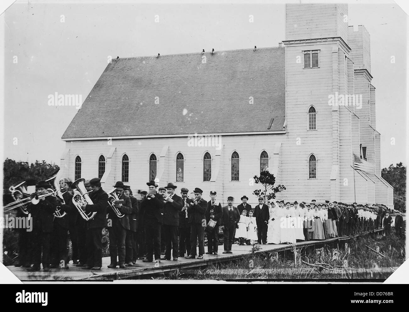 Cette photographie montre une procession quittant l'église Metlakahtla à la suite d'une cérémonie de mariage. L'image capture les traditions culturelles et religieuses associées à cet événement à Metlakahtla. Banque D'Images