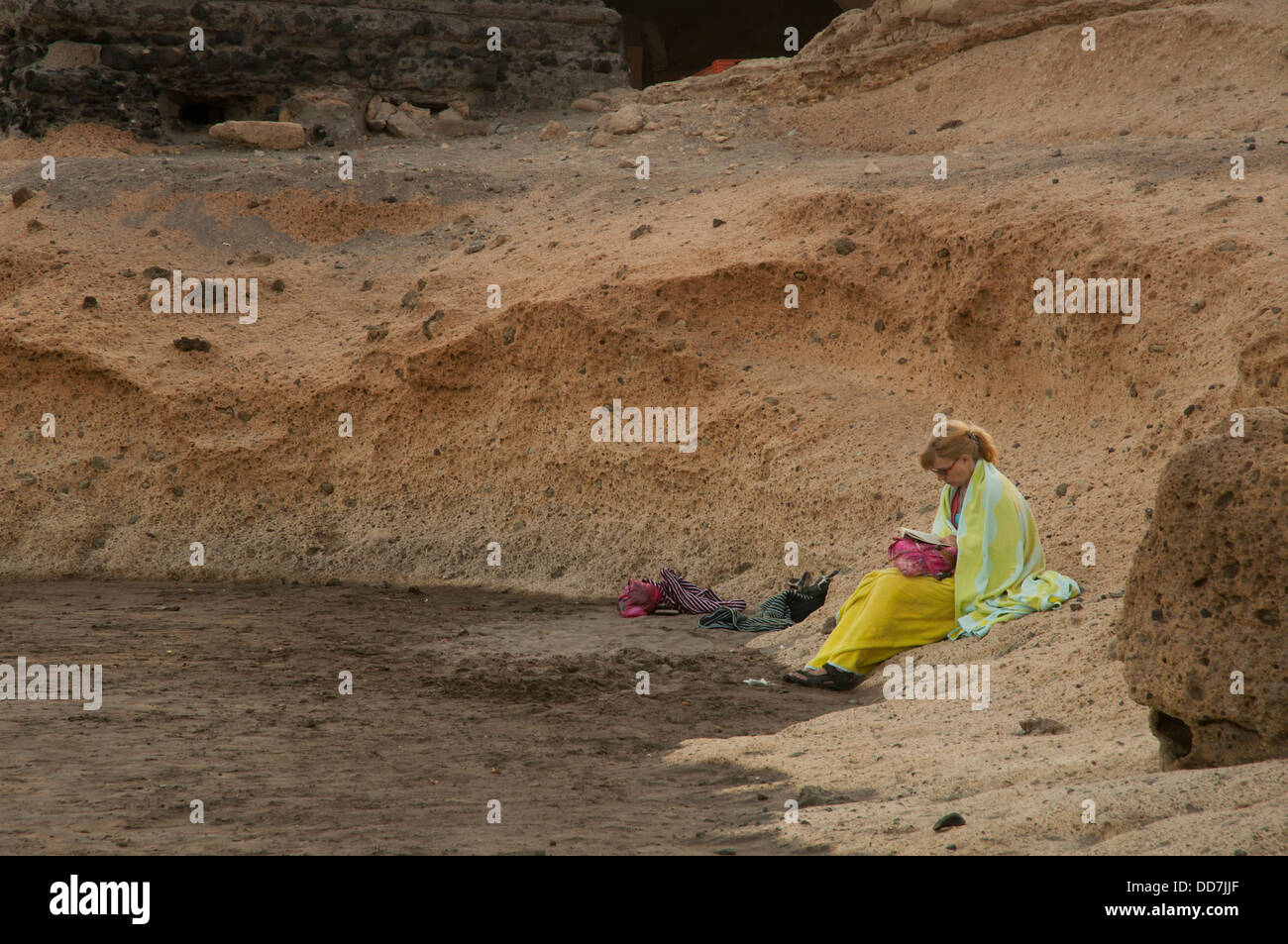 Habillée de couleurs femme assise seule sur la plage à Ténérife Banque D'Images