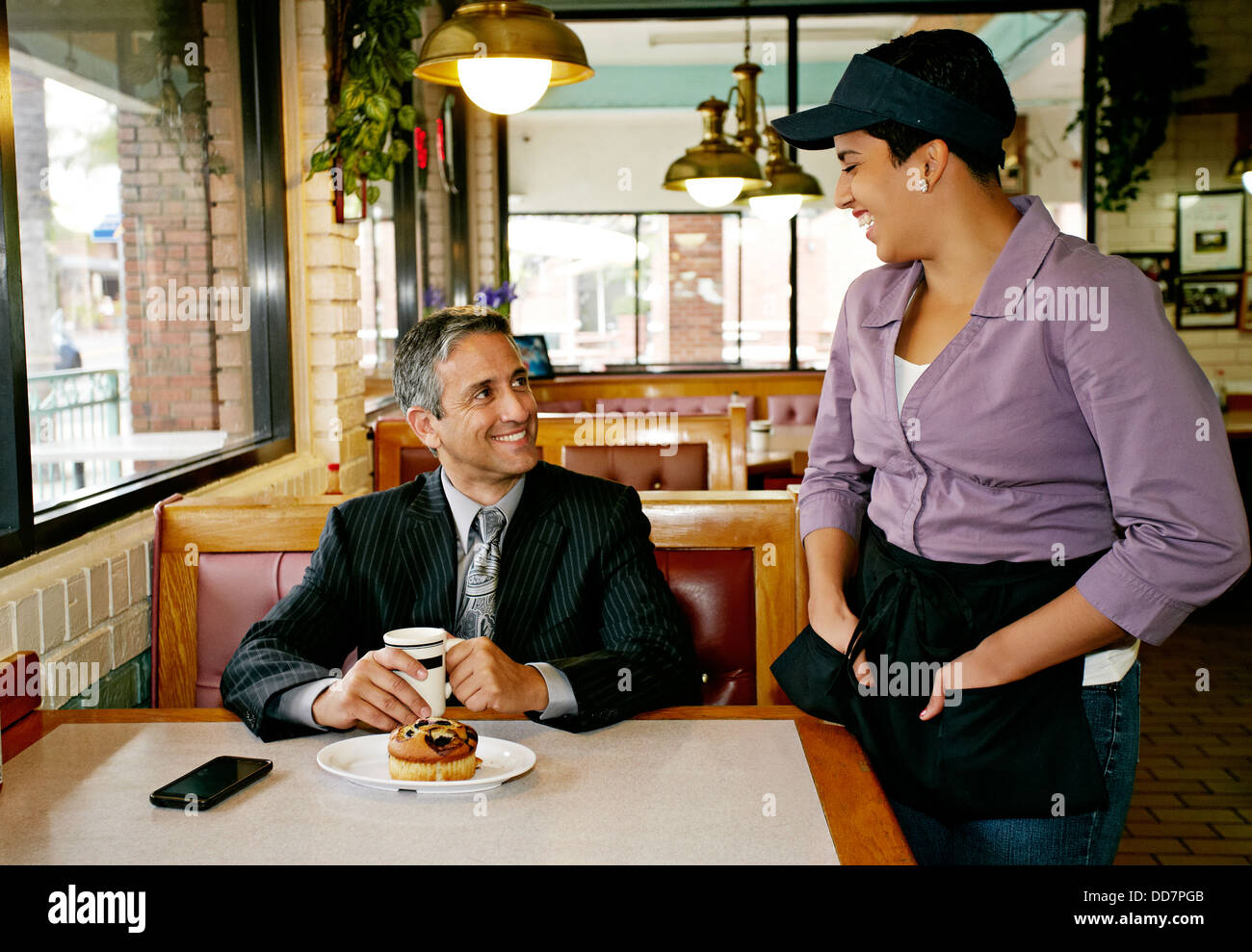 Hispanic waitress talking to businessman in restaurant Banque D'Images