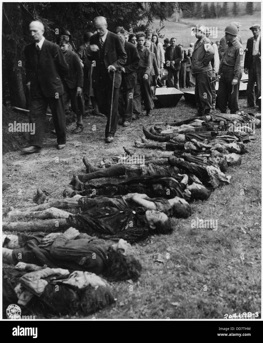 Des civils allemands, sous la direction de médecins américains, passent devant un groupe de 30 femmes juives qui avaient péri de faim. Cette sombre photographie capture les horreurs de l'Holocauste et les conditions brutales qui ont conduit à la mort de millions de personnes pendant la première Guerre mondiale Banque D'Images