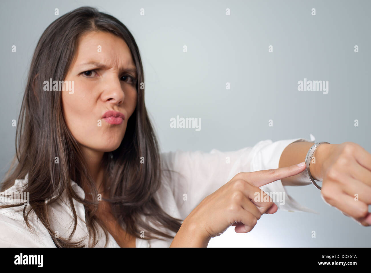 Irrité businesswoman touchant sa montre et froncer comme elle est maintenue en attente d'un rendez-vous par un client fin unpunctual Banque D'Images