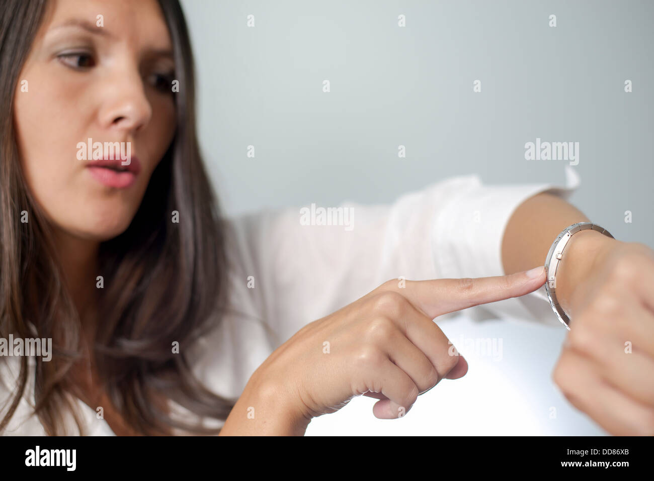 Irrité businesswoman touchant sa montre et froncer comme elle est maintenue en attente d'un rendez-vous par un client fin unpunctual Banque D'Images