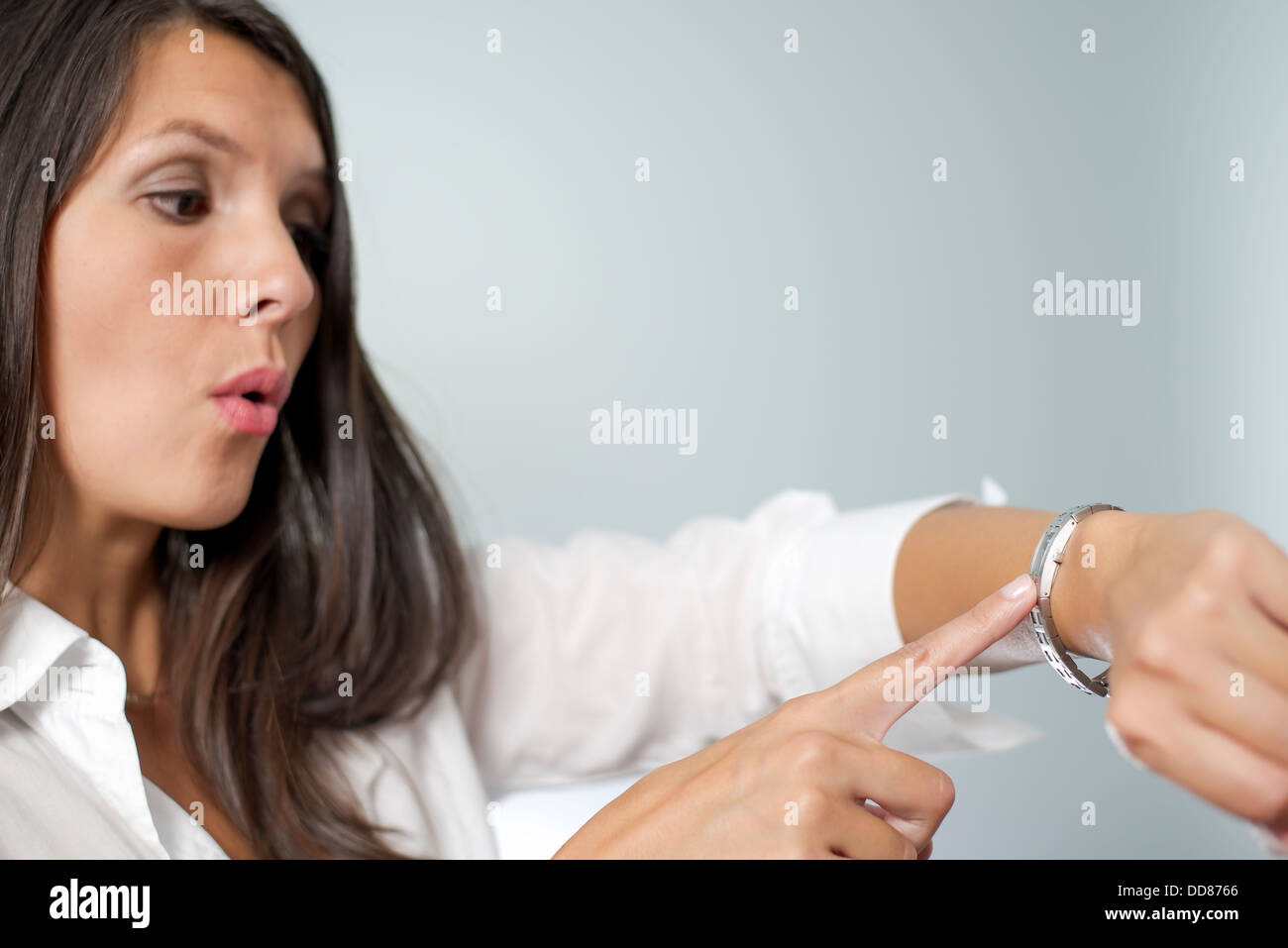 Irrité businesswoman touchant sa montre et froncer comme elle est maintenue en attente d'un rendez-vous par un client fin unpunctual Banque D'Images